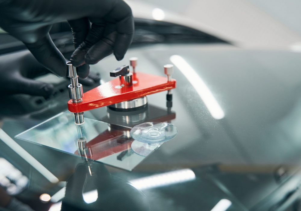 Closeup repair of cracked car windshield. Auto windshield crack fixing. Professionally repairing